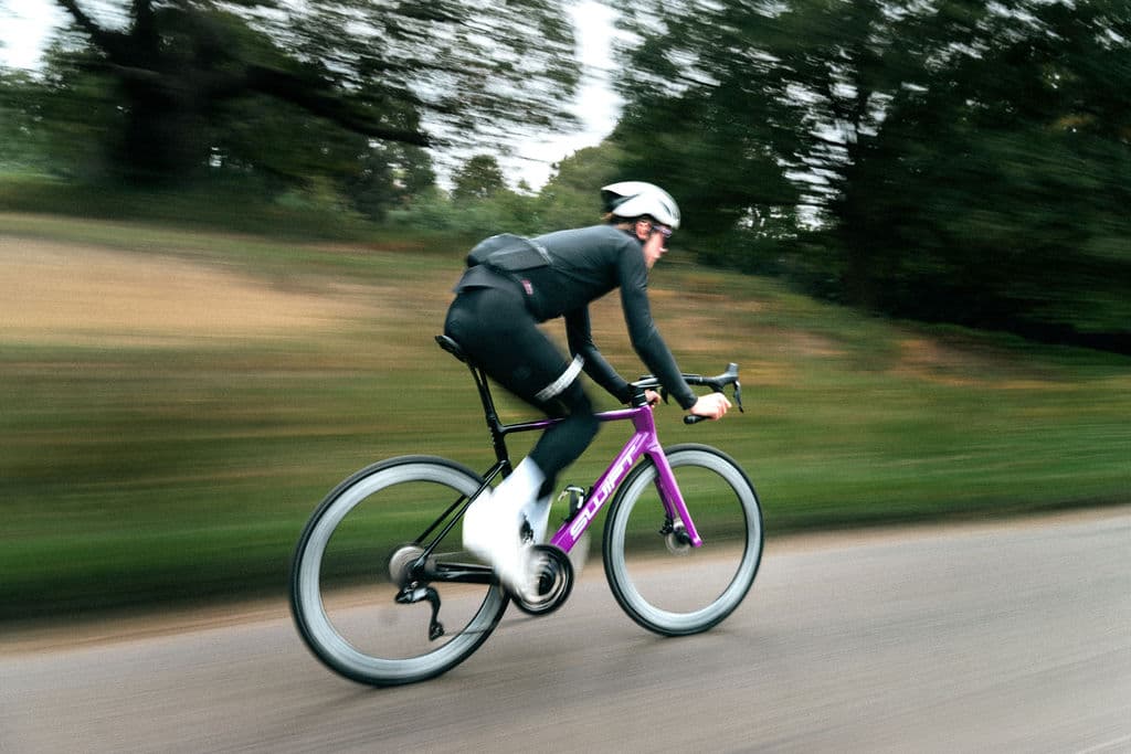Cyclist at speed with a purple SWIFT bike, motion blur in the park